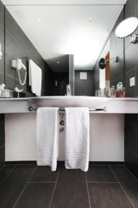 un baño con toallas blancas colgadas en una encimera en Hotel Central, en Obersaxen