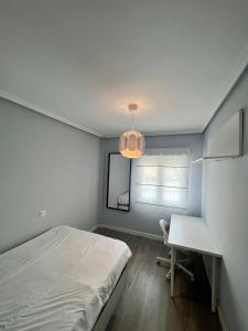 1 dormitorio con cama, escritorio y lámpara en Piso Minimalista Reformado, en San Vicente de la Barquera
