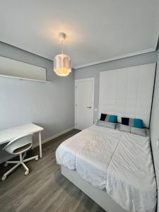 1 dormitorio con cama blanca y escritorio en Piso Minimalista Reformado, en San Vicente de la Barquera