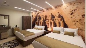 two beds in a room with a wall with a mural at Celia Pyramids View inn in Cairo