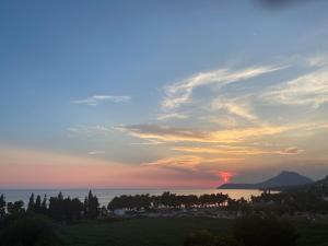 a sunset over the ocean with trees and the sky at Ačanski Apartments Bar in Bar