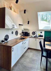 uma cozinha com armários brancos, uma mesa e uma janela em Apartamenty na Wyrszczku em Istebna