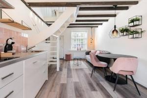 een keuken met witte kasten en een tafel en roze stoelen bij Vakantiehuisje Dichtbij Zee in Vlissingen