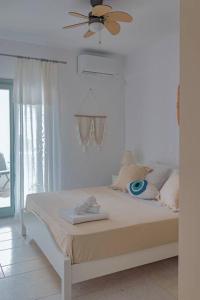 a white bedroom with a bed with a ceiling fan at Martha's filoxenia in Drios