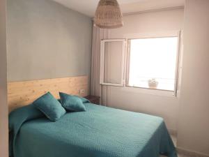 パラモスにあるApartamento a 150 metros de la playa en la Foscaのベッドルーム1室(青い枕のベッド1台、窓付)