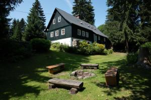 a black house with benches in front of it at Chalupa Bedřichov in Bedřichov