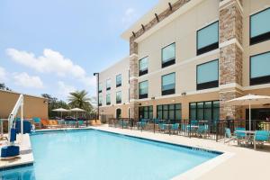 a swimming pool in front of a building with chairs and umbrellas at Holiday Inn Express & Suites Gulf Breeze - Pensacola Area, an IHG Hotel in Gulf Breeze