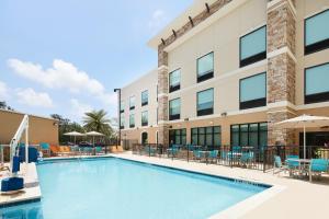 a swimming pool in front of a building with chairs and umbrellas at Holiday Inn Express & Suites Gulf Breeze - Pensacola Area by IHG in Gulf Breeze
