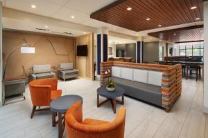 a lobby with orange chairs and a piano at Holiday Inn Express & Suites Gulf Breeze - Pensacola Area, an IHG Hotel in Gulf Breeze