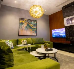 a living room with a green couch and a chandelier at Dana Hotel in Buraydah
