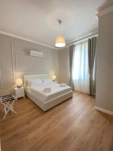 a white bedroom with a large white bed and wooden floors at FOUR LIONS VILLA GUESTHOUSE in Pisa