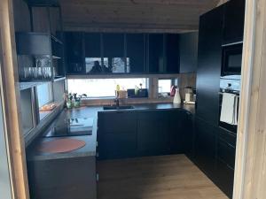 a kitchen with dark blue cabinets and a sink at Ny hytte med sjøen. Fantastisk utsikt. Lofoten in Svensgam +40 photos