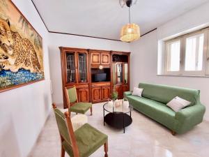 un soggiorno con divano e sedie verdi di Farfalle a Petacciato