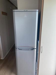 a white refrigerator freezer sitting in a kitchen at Cosy holiday home at Romney Sands in New Romney