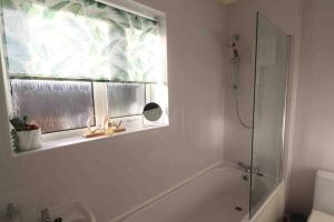 baño con ducha y bañera y ventana en Spacious three bedroom house with off road parking en Birmingham