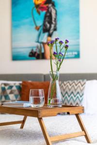 einen Tisch mit einer Vase mit Blumen und einem Glas in der Unterkunft Mare Apartments in Palanga