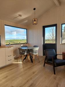 a dining room with a table and chairs and windows at Iceland Inn Cabin in Selfoss
