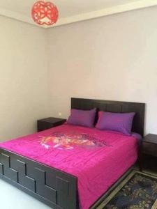 um quarto com uma cama rosa e almofadas roxas em Le 21 Armada Tower em Bouznika