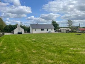 un gran campo con una casa en el fondo en Higgins House en Ballyhaunis