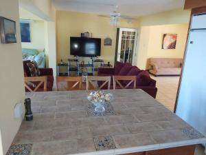 sala de estar con mesa y TV en When we say Beach Front, we mean on the BEACH!, en Luquillo