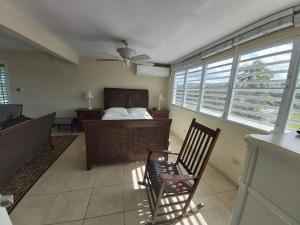 1 dormitorio con 1 cama, 1 silla y ventanas en When we say Beach Front, we mean on the BEACH!, en Luquillo
