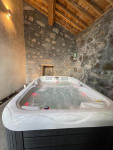 Cette chambre dispose d'une baignoire et d'un mur en pierre. dans l'établissement Casa Pyrrhula Murina - Private Jacuzzi, à Nordeste