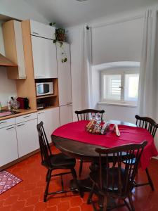 uma cozinha com uma mesa e cadeiras com uma toalha de mesa vermelha em Volta 8 rooms em Trieste