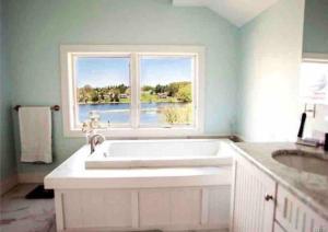 La salle de bains est pourvue d'une grande baignoire blanche et d'une fenêtre. dans l'établissement Salmon River View, à Pulaski