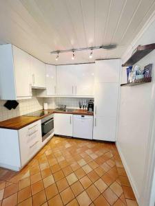 uma cozinha com armários brancos e piso em azulejo em Your Ultimate Group Getaway - Central in Vibrant Bislett em Oslo