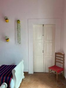 Cette chambre comprend un lit, une chaise et une porte. dans l'établissement CASA TERRA LINDA, à San Luis Potosí