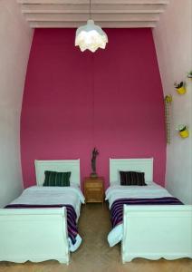 - 2 lits dans une chambre avec un mur rose dans l'établissement CASA TERRA LINDA, à San Luis Potosí