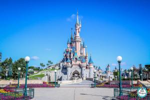 Un castello di disney in un parco in una giornata limpida di Appartement Disneyland Paris a Bussy-Saint-Georges