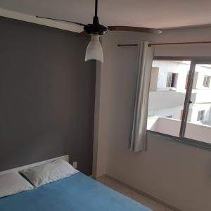 1 dormitorio con ventilador de techo y ventana en Cobertura vista para o mar e piscina en Piúma