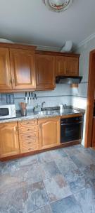 eine Küche mit Holzschränken und einem Waschbecken in der Unterkunft Apartamentos Rurales San Esteban de los Buitres - Illano 