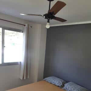 a ceiling fan in a bedroom with a window at Cobertura vista para o mar e piscina in Piúma