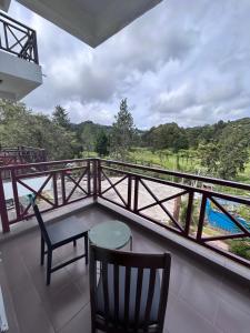 a balcony with a table and chairs and a view at Cameron Iris AiSHomestay in Tanah Rata