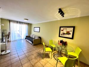 La Tejita的住宿－Apartment in La Tejita (El Medano)，客厅配有玻璃桌和黄色椅子