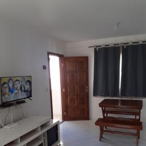 a living room with a tv and a wooden door at Apartamento 204 vista para o mar e piscina in Piúma