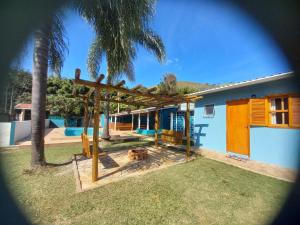 un parque infantil frente a una casa con una palmera en Suites Chacara Madu, en Santo Antônio do Pinhal
