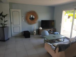a living room with a couch and a table and a mirror at Maison spacieuse au calme à 5 min de la ville in Aigné