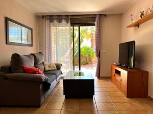 ein Wohnzimmer mit einem Sofa und einem TV in der Unterkunft Apartament with Garden in La Tejita