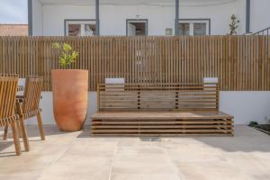 un banco de madera sentado junto a una valla de madera en Bento Caraça Terrace, en Alcácer do Sal