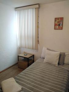 a small bedroom with a bed and a table at Depa Cholulita in Cholula