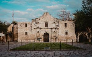 un antiguo edificio de piedra con un patio de césped delante en Casa Dolce Vita by the Alamodome en San Antonio