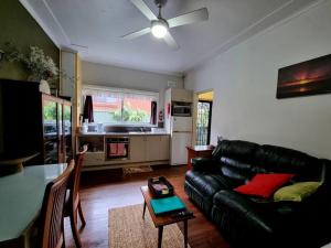 a living room with a black leather couch and a table at Kurranulla Sapphire - U3 in Cronulla