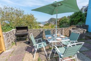 een tafel en stoelen met een parasol en een grill bij The Tempest, sea views, coastal & rural walks. in Ilfracombe