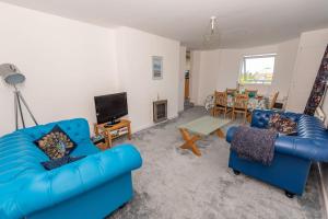 a living room with two blue chairs and a tv at The Tempest, sea views, coastal & rural walks. in Ilfracombe