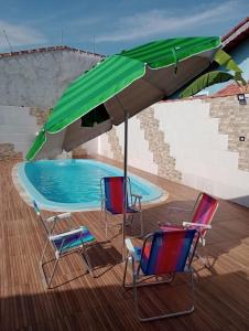 - deux chaises et un parasol à côté de la piscine dans l'établissement Casa na praia com piscina e churrasqueira, à Itanhaém