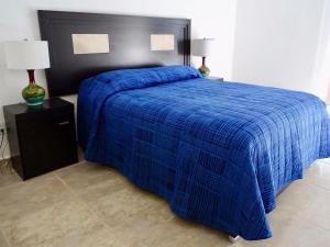 un letto blu con testiera nera e coperta blu di Casa Los Amores a Bucerías