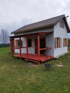 une petite maison avec une terrasse couverte rouge sur un champ dans l'établissement Domek całoroczny, à Zastań